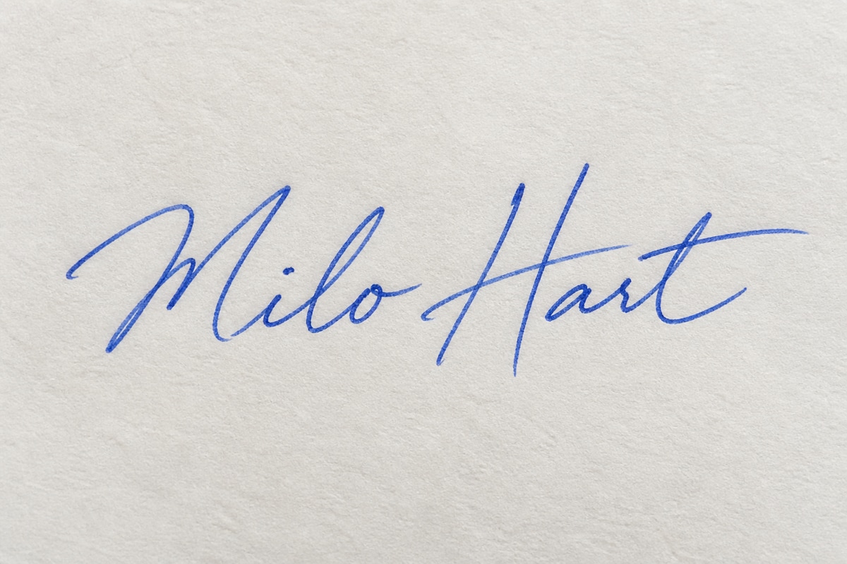 Firma ficticia de Milo Hart con tinta azul sobre papel blanco cálido